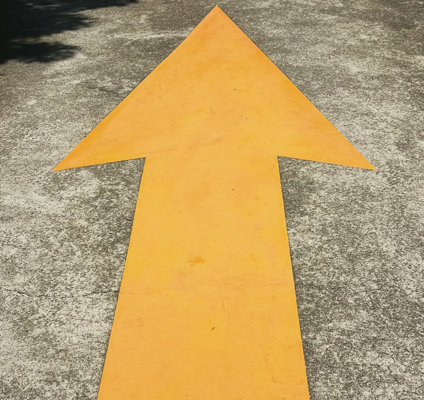 a yellow arrow painted on the ground in a parking lot